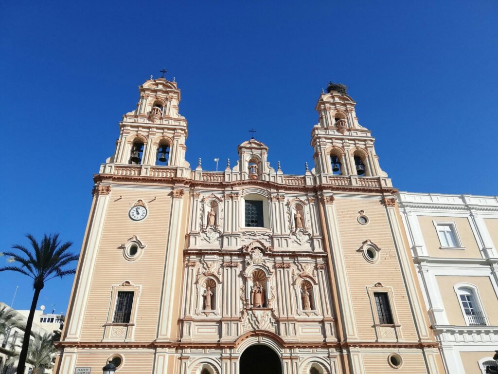 View of the beautiful ornate facade of Huelva Cathedral under a clear blue sky, an iconic landmark in Spain.