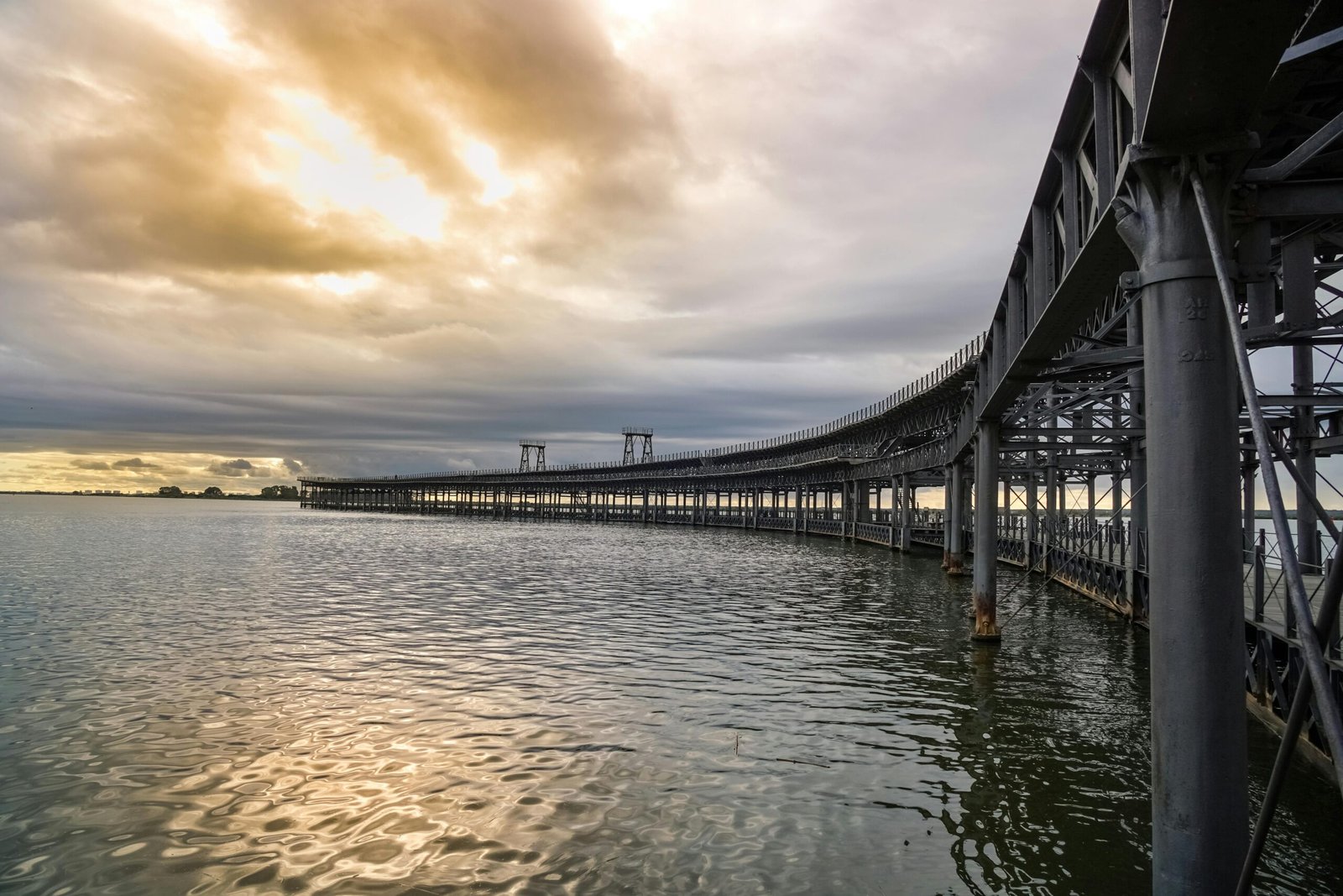 Scenic view of the Rio Tinto Pier at sunset reflecting in Huelva's calm waters.